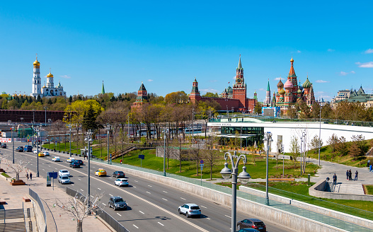 Moscow, Russia - April 29, 2019: Embankment and city traffic near Zaryadye park, Kremlin towers and St Basil Cathedral in sunny day