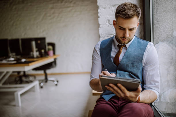 istock Business man sitting by the window and using digital tablet 1147855368