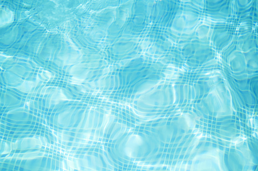 Defocus blurred transparent blue colored clear calm water surface texture with splashes and bubbles. Trendy abstract nature background. Water waves in sunlight with copy space. Blue watercolor texture