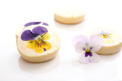 vanilla cookies decorated with edible flowers on a white background
