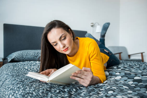 istock Brunette woman reading a book on the bed 1147875838