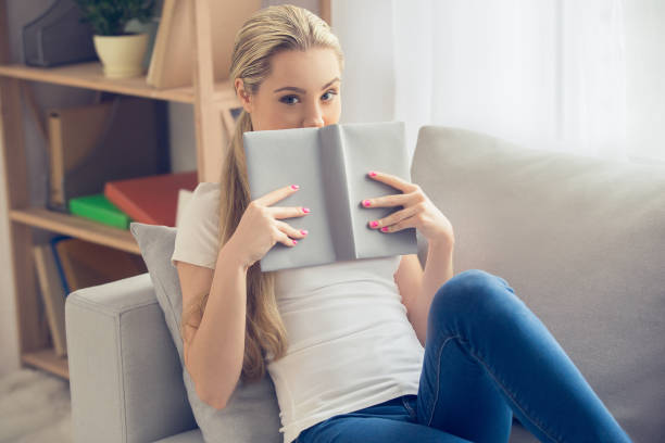 istock Young woman reading book at home leisure 1147876834