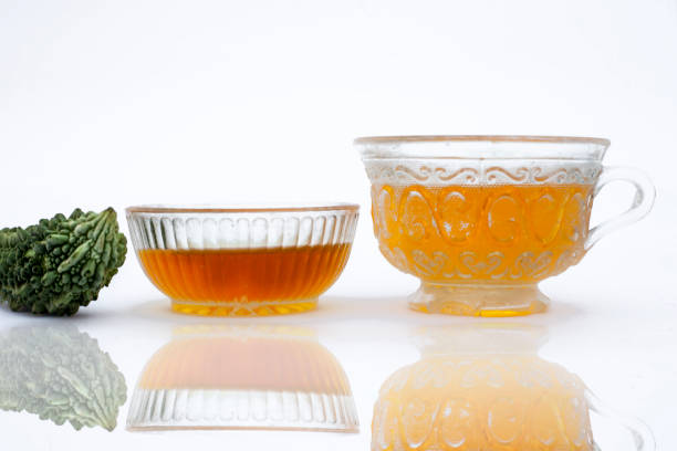 Popular detoxifying herbal tea isolated on white i.e. Bitter melon or Bitter cucumber tea isolated along with honey and its ingredients with their reflection also.