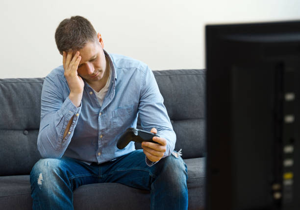 istock Upset man sitting on the sofa with gamepads. 1147881480