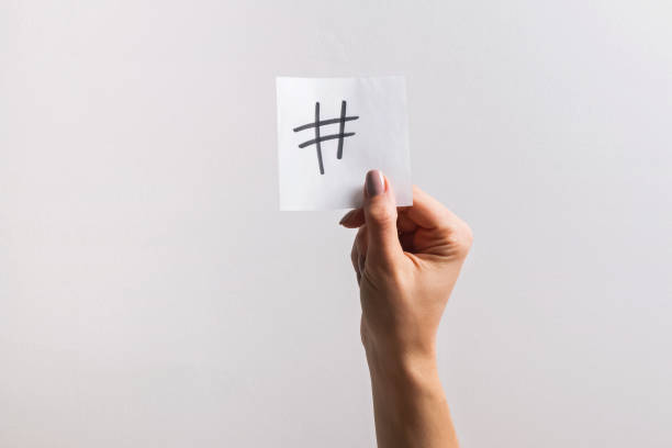 istock Woman's hand holding small paper with drawn hashtag symbol on it 1147881685