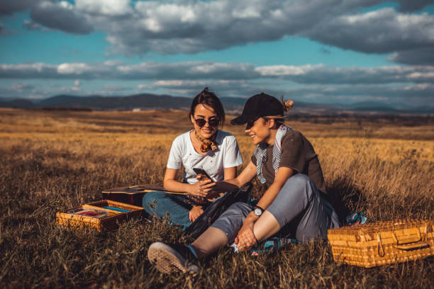 istock Happy young woman having a picnic and using smart phone 1147883358