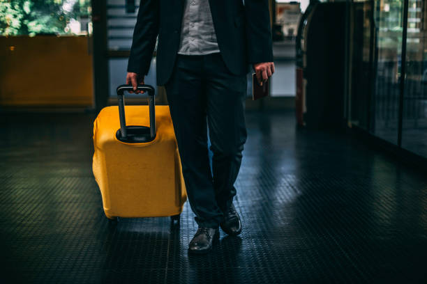 istock Man in suit pulling yellow suitcase at the airport 1147884150