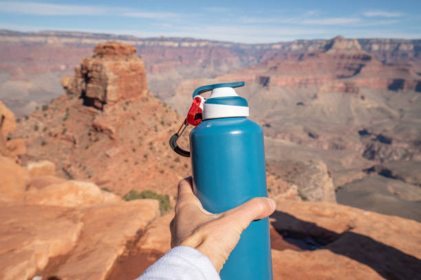 point de vue de la bouteille d'eau de fixation de main s'étendant vers le grand canyon, concept de voyage - grand view point photos et images de collection