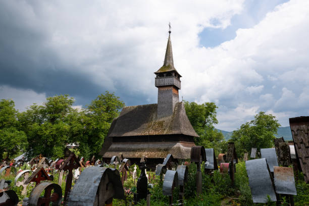 Ieud, Maramures, Romania - July 9, 2018: Ieud Hill Church and its graveyard, the oldest wood church in Maramures, Romania under a dramatic sky. The Church belongs to a collection of Wooden Churches of Maramures, UNESCO World Heritage Site.
