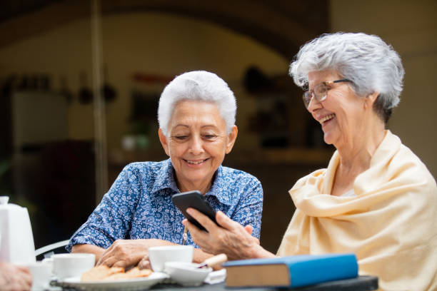 istock Two elderly women sitting and looking at mobile phone 1147891383
