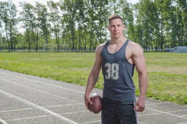 istock Young muscular quarterback with a ball at the stadium 1147901020