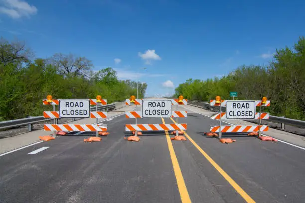 Road closed signs on a bridge over the swollen Illinois river after flooding on the roadway.