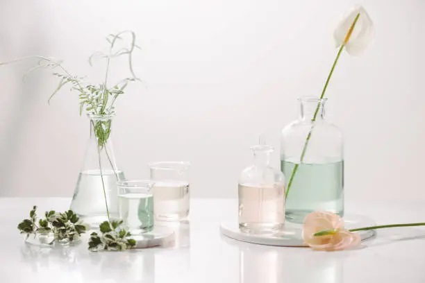 Perfume oils concept. Laboratory glassware with infused floral water on table