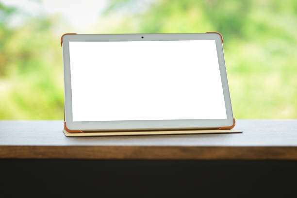 istock tablet on table isolated screen - Digital tablet compute or laptop blank screen on table nature green background 1147912476