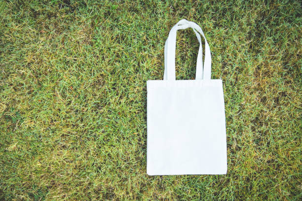 istock White tote canvas fabric eco bag cloth shopping sack on green grass background / Zero waste Use less plastic say no plastic bag pollution problem 1147912488
