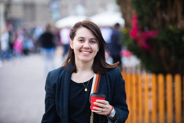 frau zu fuß mit rotem papier kaffeetasse - causality stock-fotos und bilder