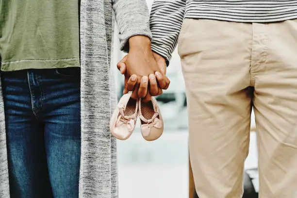 Cropped shot of an unrecognizable couple holding pink baby shoes