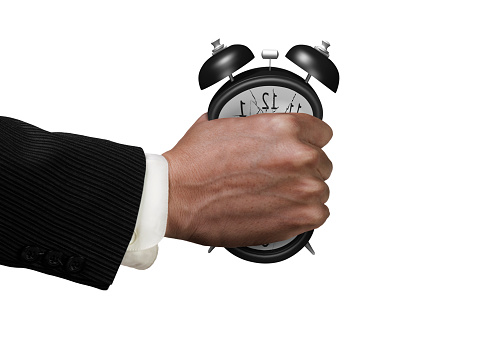 Time is not enough concept. Businessman's fist clenched the deformed alarm clock in anger, isolated on white background.