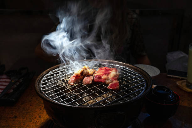 Cooked and raw beef on charcoal grill with smoke stock photo