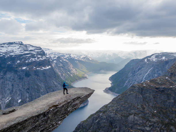 istock Norway - Young man standing at the edge of Trolltunga 1147920178