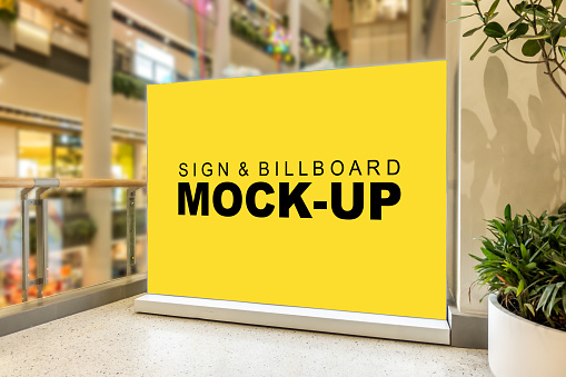 Mock up blank large yellow screen billboard or signboard stand with clipping path in shopping mall, empty space for message or media advertisement indoors with the view on the right