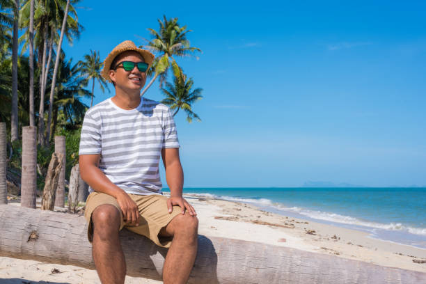 istock Happy young asian man on beach in vacation time. 1147922032