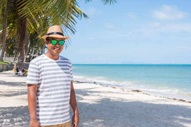 istock Happy young asian man on beach in vacation time. 1147923499