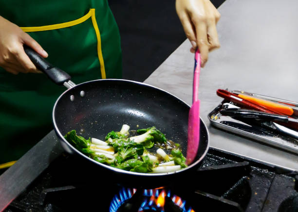 istock Chef cooking with flame in a frying pan on a kitchen stove 1147926532