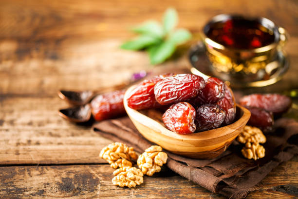 Fresh Medjool Dates Fresh Medjool Dates in a bowl with tea on wooden background.. Ramadan kareem. date fruit stock pictures, royalty-free photos & images