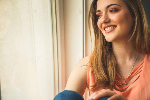 istock Smiling young woman by the window 1147929126