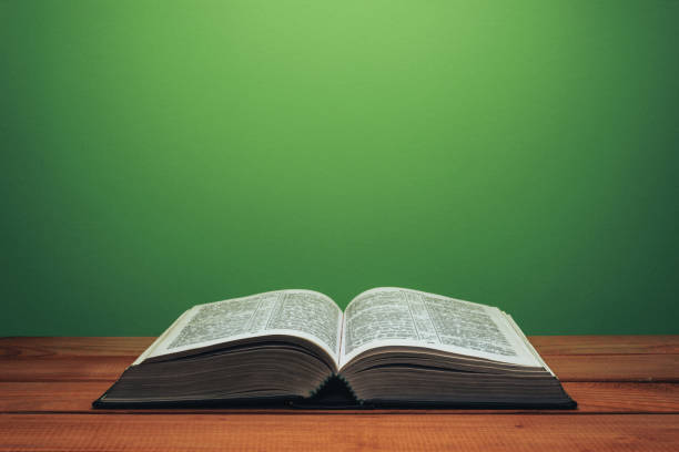 istock Bible on a red wooden table. Beutiful green wall background. 1147930941