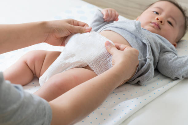 istock Mother changing diaper for her son on white bed in bedroom 1147933704
