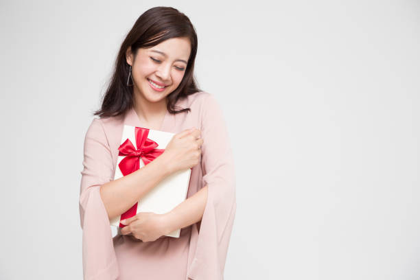 happy beautiful asian woman smile with red gift box and copy space white living room background. teenage girls in love, receiving gifts from lovers. new year, christmas and valentines day concept - suitor imagens e fotografias de stock