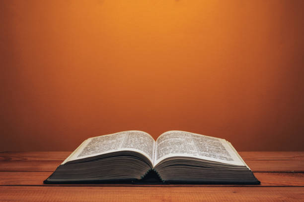istock Bible on a red wooden table. Beutiful orange wall background. 1147934288