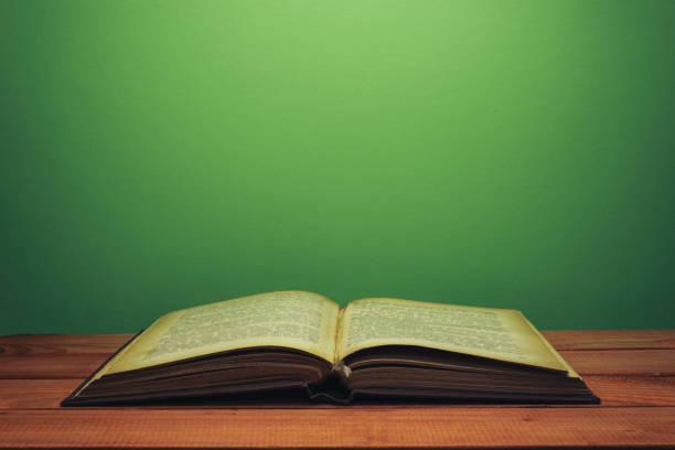 istock Old book on a red wooden table. beautiful green wall background. 1147934354