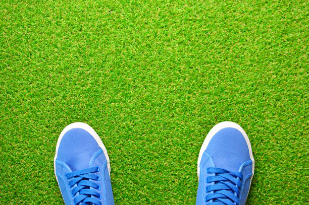 istock Blue sneakers shoes on a green artificial grass. View above. Copy space. 1147940564