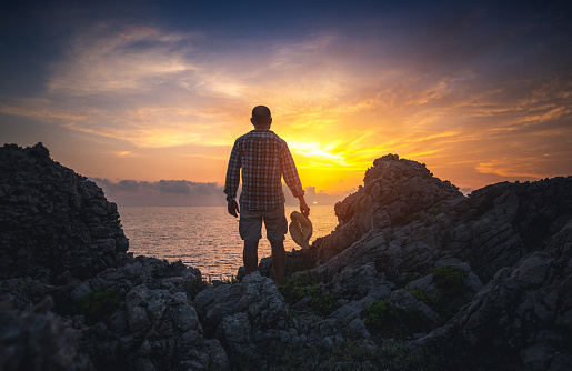 Man stands on rocks and watches sunset