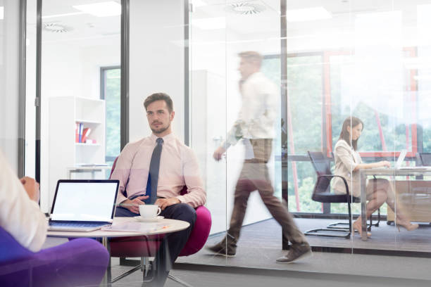 istock Businessmen discussing in boardroom while colleagues working in background at office 1147943242