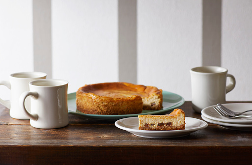 Three mugs with cheesecake placed on a wooden table.