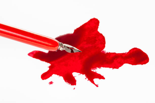 istock sharp nib in red dip pen over red ink stain 1147945876