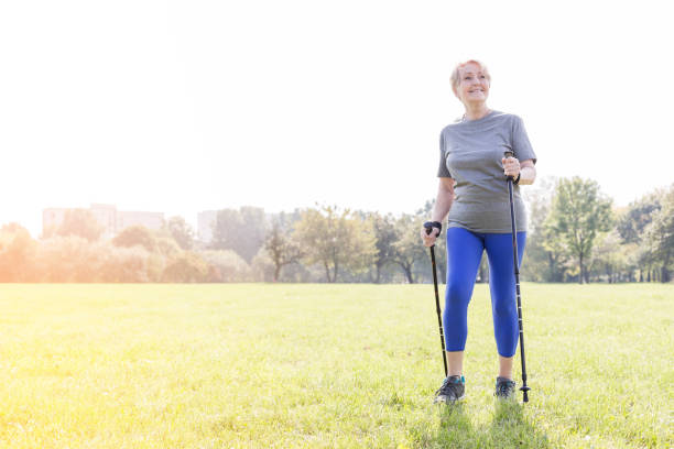 istock Smiling senior woman using trekking poles while walking in park 1147947341