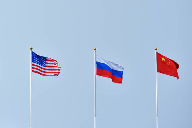 Beautiful and bright flags of the Russian Federation, China and the United States of America against the sky. Flags of Russia, China and America as a symbol Multipolar world and equality stock photo