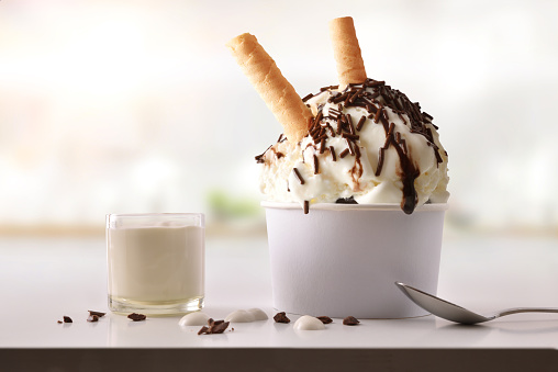 Ice cream cup with choco on white table homemade with kitchen background. Horizontal composition. Front view.