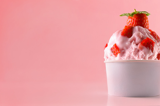 Strawberry ice cream cup on table isolated close up. Horizontal composition. Front view.