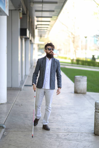 istock Blind and bearded man with a walking stick on the street 1147959794