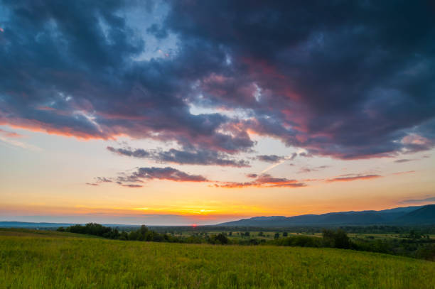 istock Colorful and dramatic sunset over a green field 1147960063