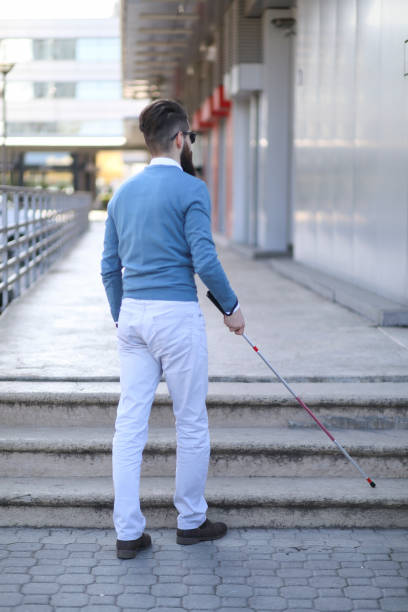 istock Blind and bearded man with a walking stick on the street 1147960117