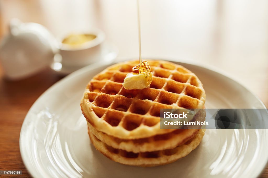 Wake up to the deliciousness of waffles Shot of a stack of waffles topped with a cube of butter and syrup on a plate Waffle Stock Photo