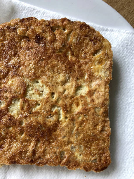 Stock photo of homemade eggy bread often called French toast, being eaten for breakfast with crispy smoked bacon. The French toast has just been fried and is pictured on kitchen paper. imagen de pan casero grasienta grasoso/tostadas francesas rebanadas para el desayuno, cocinadas en sartén antiadherente, descansando en papel de tejido de la cocina para absorber el exceso de aceite de cocina de tostadas francesas (wholemeal, rebanada de