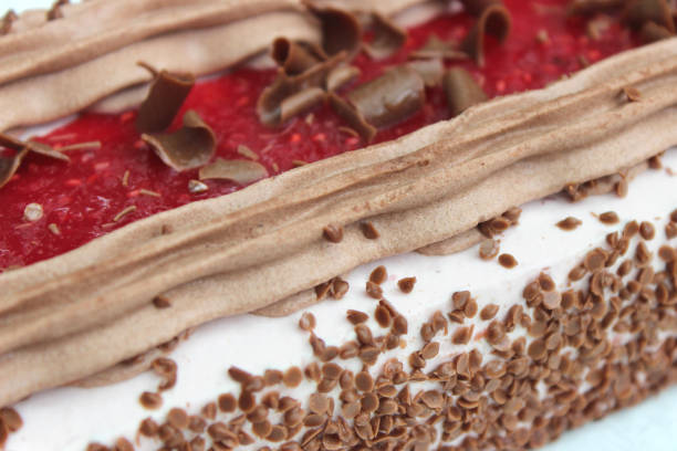 istock Image of homemade rectangular shaped chocolate cake with layers of sponge cake, fresh whipped cream, raspberry jam / raspberry coulis, cocoa and chocolate butter icing cream, chilled and ready to eat as an indulgent pudding desert after dinner party meal 1147961043